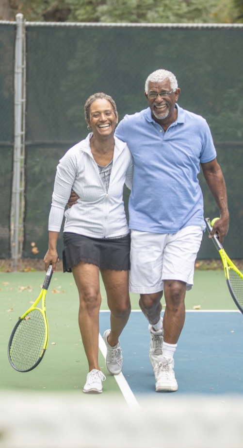 couple on tennis court with rackets and laughing for some reason