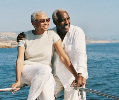couple on boat railing in front of water and smiling for some reason
